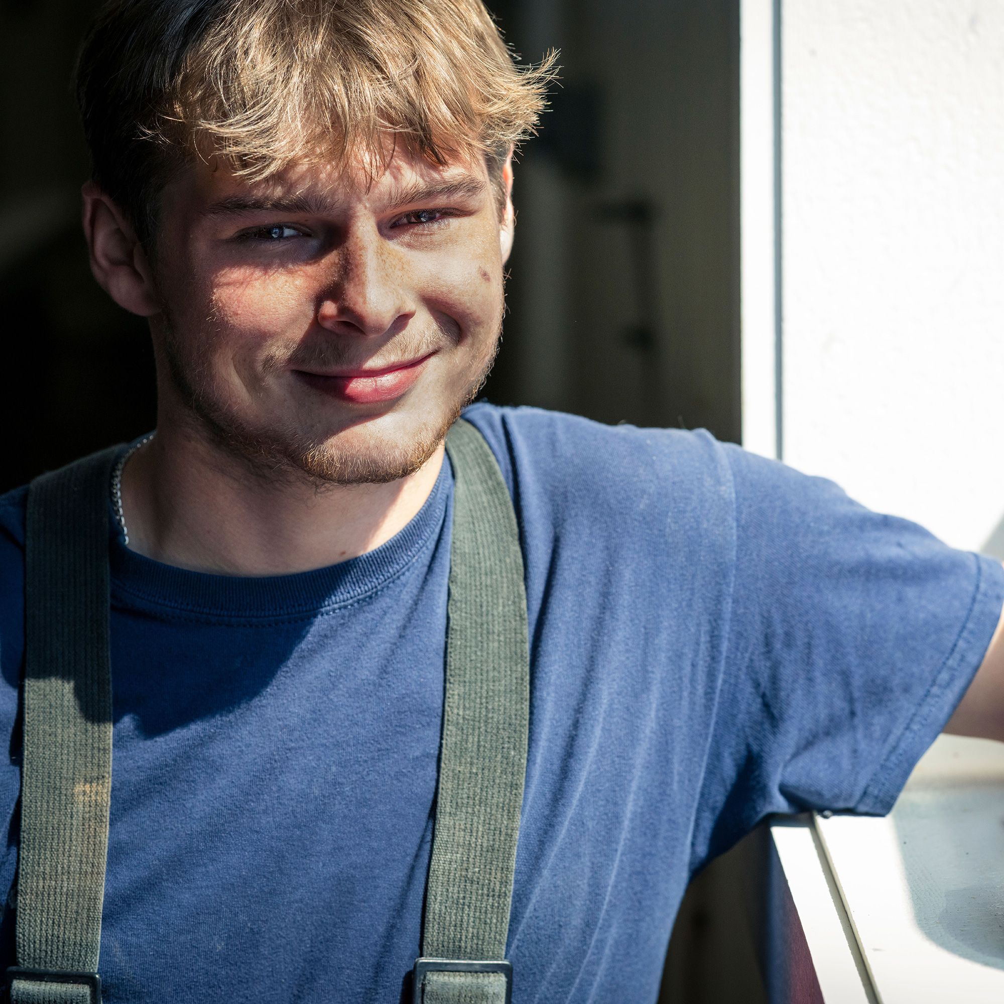 Young man with blonde hair smiling and looking into the camera.